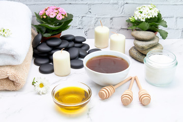 Fototapeta na wymiar Bowls of honey and oil for skin treatment along with candles