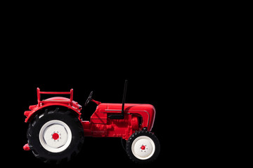Naklejka premium Red toy tractor. Isolate on a black background. Selective focus.