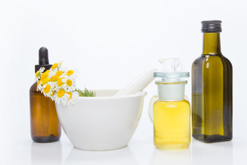 Healing herbs with mortar and bottle of essential oil.