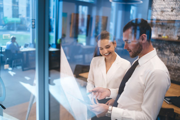 Smiling colleagues talking about project and writing on flip chart