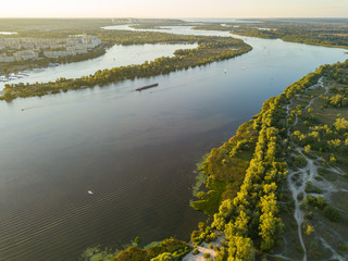 Obraz premium Aerial drone view. Bank of the Dnieper River in Kiev in the evening in the rays of the setting sun.