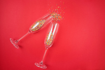 Champagne glass with colorful sugar sprinkles on red background.