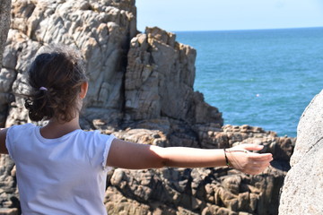 Mädchen an der Küste der Bretagne schaut hinaus auf das weite Meer