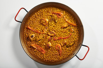 Traditional paella typical of Spain in traditional frying pan on white background