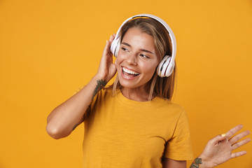 Image of joyful woman smiling and listening music with headphones