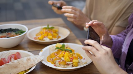 Two femaes taking pictures of their vegan lunch with the smartphones. Healthy vegan life style concept.