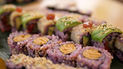 Close up of various kinds of colorful sushi rolls served on bamboo leaves