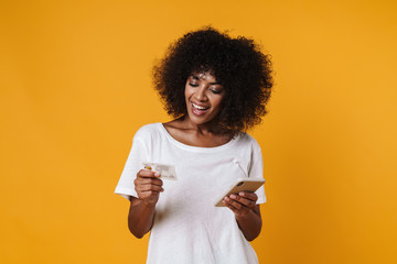 Image of african american girl holding credit card and mobile phone