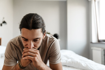 Young man in depression sitting on bed