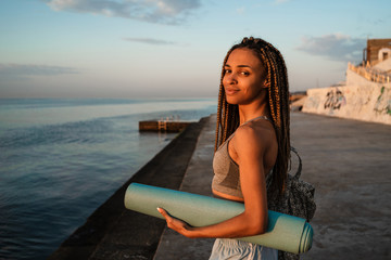 Fototapeta na wymiar Cheerful african young sport girl walking at the beach