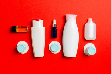 Top view of means for face care: bottles and jars of tonic, micellar cleansing water, cream, cotton pads on colored background. Bodycare concept with empty cpace for your ideas