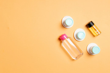 Set of travel size cosmetic bottles on colored background. Flat lay of cream jars. Top view of bodycare style concept