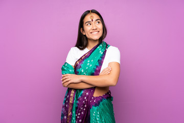 Young Indian woman with sari over isolated background looking up while smiling