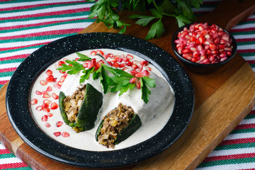 High angle shot of Chiles en nogada in a plate on a wooden board on the table
