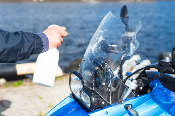 Man cleaning of motorcycle windshield