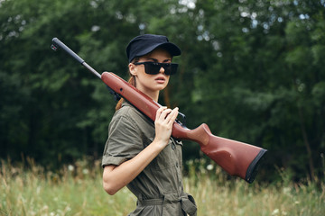 Woman on outdoor holding a weapon on his shoulder sunglasses green jumpsuit 