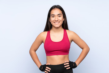 Young Indian sport woman isolated on blue background posing with arms at hip