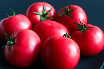 Red fresh tomatoes on dark background