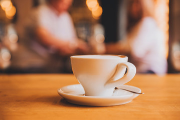 Cup with saucer and spoon on a brown wooden table in a cafe