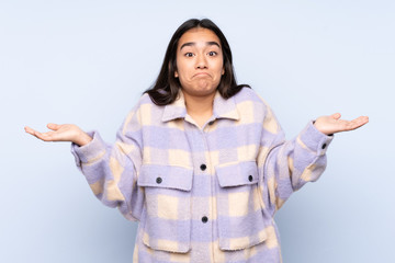 Young Indian woman isolated on blue background making doubts gesture