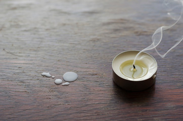 A smoking candle on a wooden table.