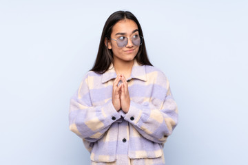 Young Indian woman isolated on blue background scheming something