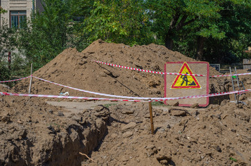 Wooden billboard with sign carrying out repair earthworks next to the dug trench.