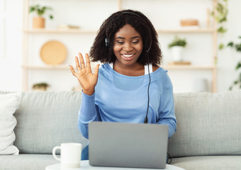Smiling black lady sitting on couch with headset