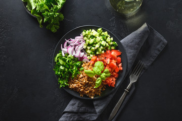 Salad of whole grain cereal spelt with seasonal vegetables, tomato, cucumber, greens in bowl on...