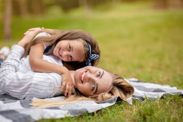Cute Mother And Daughter Embracing Lying On Blanket In Park