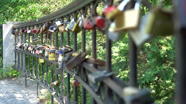Camera refocusing on locks hanging on a metal fence in the park.