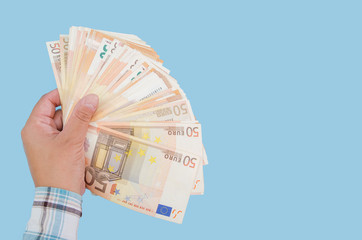 euro banknotes in a female hand on a blue background. Business concept. Copy of space. Much money. Wealth concept.