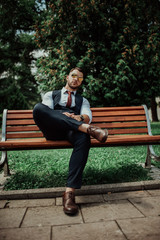 Fototapeta premium a young sexy businessman in a suit sitting in park on job break