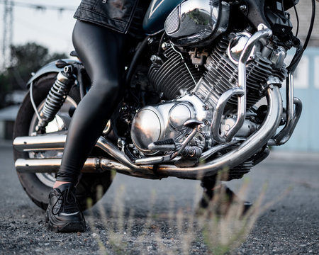 A woman in leather leggings is sitting on a motorcycle. close uo of female legs on a bike
