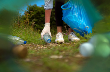Volunteer collecting bottles in the forest. View from the neck of the bottle.