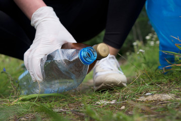 Volunteer collecting bottles in the forest. Environment pollution concept.