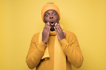 Handsome surprised african man in warm clothes is shocked with news.