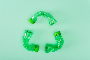  view of recycle sign from crumpled plastic bottles on green background, ecology concept