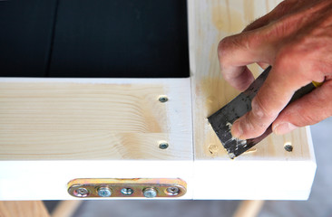 woodwork. Close-up Putty knife in man's hand. DIY worker applying filler to the wood. Removing...