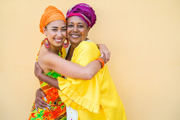 Happy mother and daughter with traditional african dresses smiling on camera - Family...