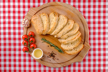 Italian Appetizer. Chiabbata and sliced white bread on wooden boards. Country style. Baguette bread path with branch cherry tomato, olive oil, garlic. Italy food. Close up.