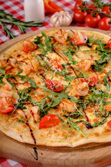 Pizza with seafood, mozzarella, mussels, octopus, squid, salmon, shrimp, cheeseand, fresh rucola and tomatoes sauce, served on a wooden board, italian restaurant background. Mediterranean food.