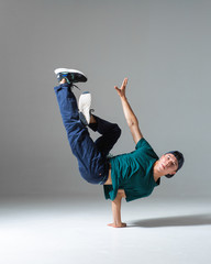 Cool b-boy dancing breakdance on the floor in studio isolated on gray background. Breakdancing...