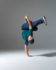 Cool b-boy dancing on the floor in studio isolated on gray background. Breakdancing school poster