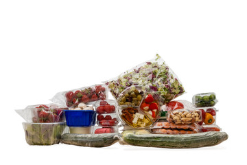 In Plastik verpackte Lebensmittel übereinander gestapelt auf weißem Hintergrund.