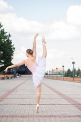 Fototapeta na wymiar Young and beautiful ballerina posing on the street
