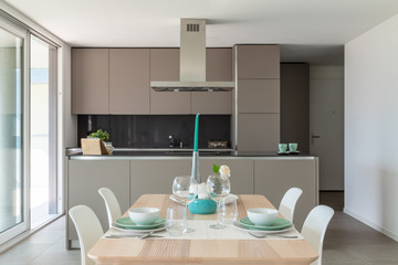 Detail of designer set table. Behind the modern designer kitchen with island