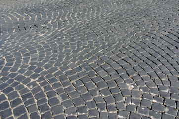 Close-up old paving stones. Cobbled street in Lviv, Ukraine. Old broken paved street. Pavement of stones. Granite cobblestones on pavement. Stone cement tile curving texture street..