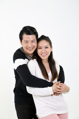 South East Asian young Chinese couple husband wife hung from behind look at camera happy smile hold hands love