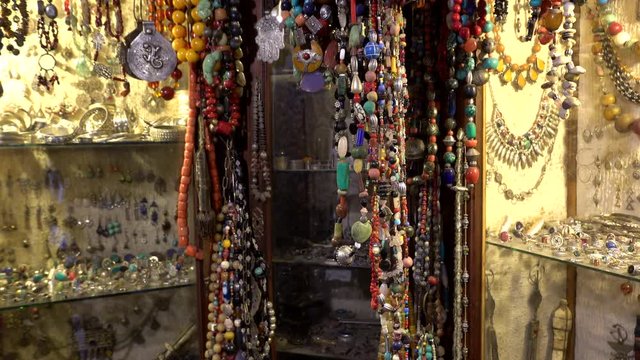 Traditional Moroccan Marrakech bazaar with arabian handmade craftsman neck decoration, beads with colorful stones, souvenirs in a market stall. 
